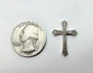 Quarter and small jeweled cross on white.