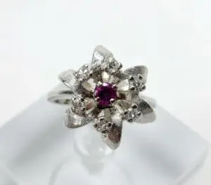 Silver floral ring with central purple gem.