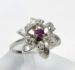 Silver ring with purple gemstone and diamonds.