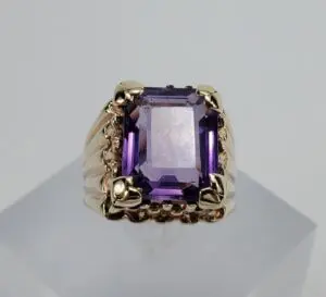 Gold ring with large purple gemstone.