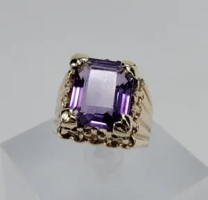 Gold ring with large purple gemstone.