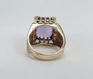 Gold ring with a purple gemstone setting.