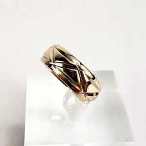 Gold geometric-patterned ring on display stand.