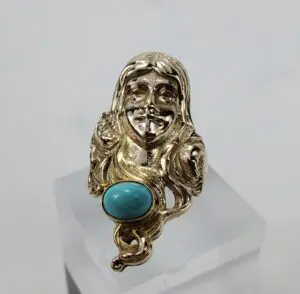 Gold ring with face and turquoise stone.