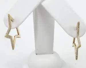Gold star-shaped earrings on display stand.
