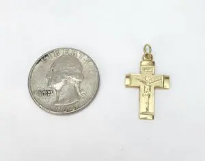 Quarter next to a gold crucifix pendant.