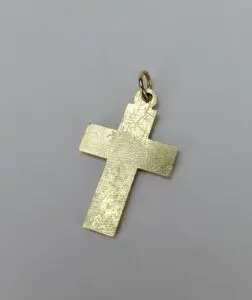 Gold cross pendant on gray background.