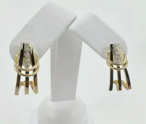 Gold and diamond earrings on display stand.