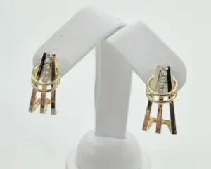 Gold and silver earrings on display stand.