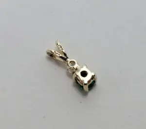 Gold pendant with gemstone on white background.