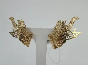 Gold dragon-shaped earrings on display stand.