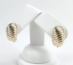 Gold twisted earrings on white display stand.