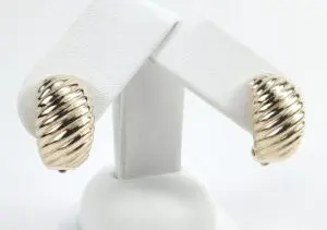 Gold-tone ribbed earrings on display stand.