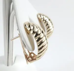 Gold textured hoop earrings on display stand.