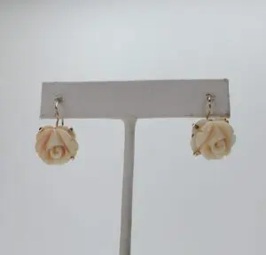 Rose-shaped earrings on display stand.