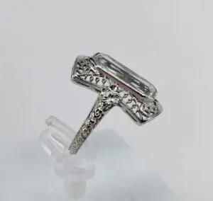 Ornate silver ring with large clear gemstone.