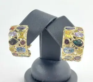 Gold earrings with colorful gemstones on display.