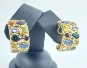 Colorful gemstone earrings on display stand.