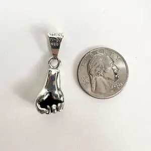 Silver fist pendant beside a quarter.