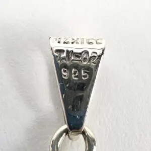 Silver pendant with engraved markings, close-up.