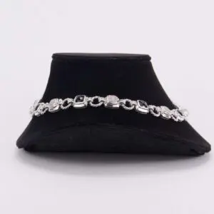 Silver bracelet with dark gemstones on display.