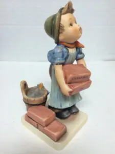Child figurine carrying bricks and bucket.