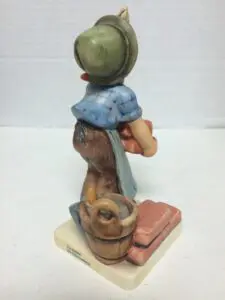 Figurine of child with basket and hat.