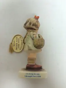 Child figurine holding a basket, side view.