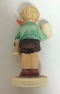 Boy figurine holding mug and carrot.