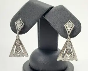 Silver geometric earrings on display stand.
