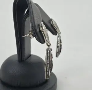 Silver earrings on a black display stand.