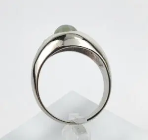 Silver ring with green gemstone on display.