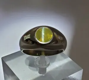 Silver ring with green gemstone on display.