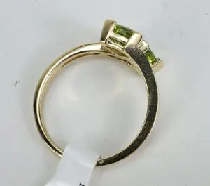 Gold ring with green gemstones on band.