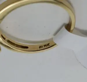 Gold ring with engraved markings and tag.