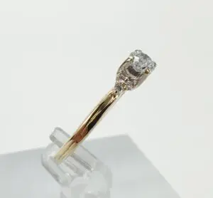 Gold ring with diamond on display stand.