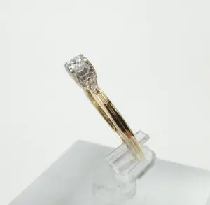 Gold ring with diamond on display stand.