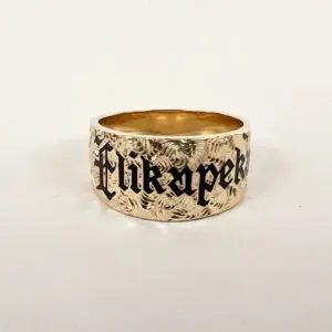 Gold ring with engraved black lettering.
