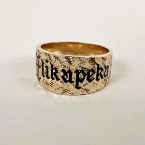 Gold ring with engraved black lettering.