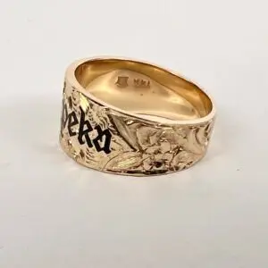 Gold ring with floral and text engraving.