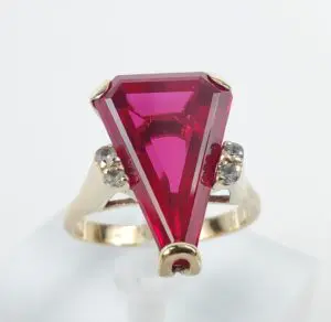 Gold ring with large triangular red gemstone.