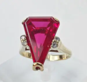 Gold ring with large triangular red gemstone.