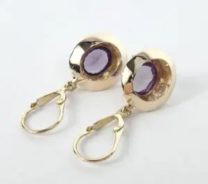 Gold earrings with purple gemstones.
