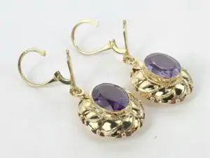 Gold earrings with purple gemstones.
