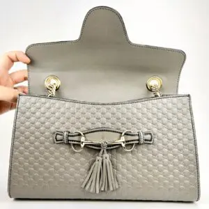 Gray handbag with open flap and tassels.