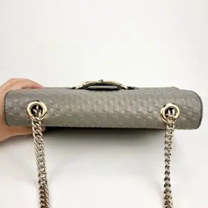 Gray handbag with chain handles, textured surface.