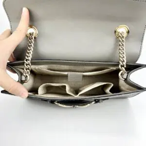 Open handbag with chain straps and compartments.