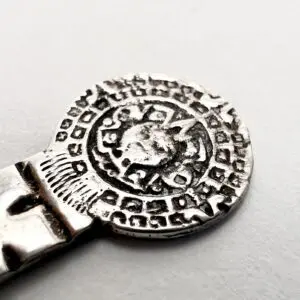 Silver metal object with intricate circular design.
