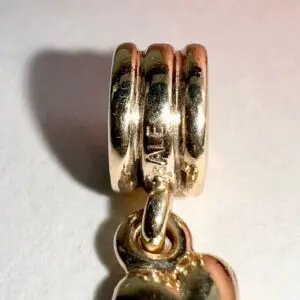 Gold charm with engraved detail close-up.