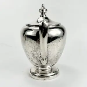Silver sugar bowl with ornate lid.